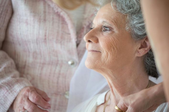 Close-up of a serene elderly woman with gray hair in a peaceful indoor setting.